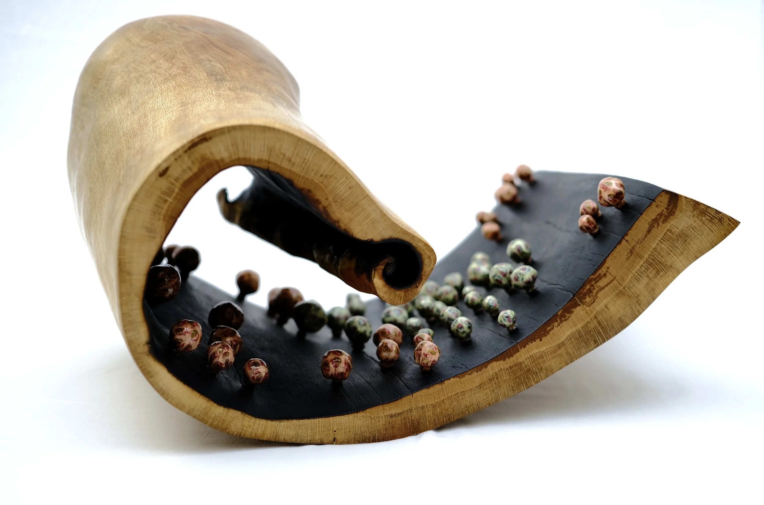 Memories — a curled wooden form like a rolled leaf, its charred inner face studded with fabric memory pods