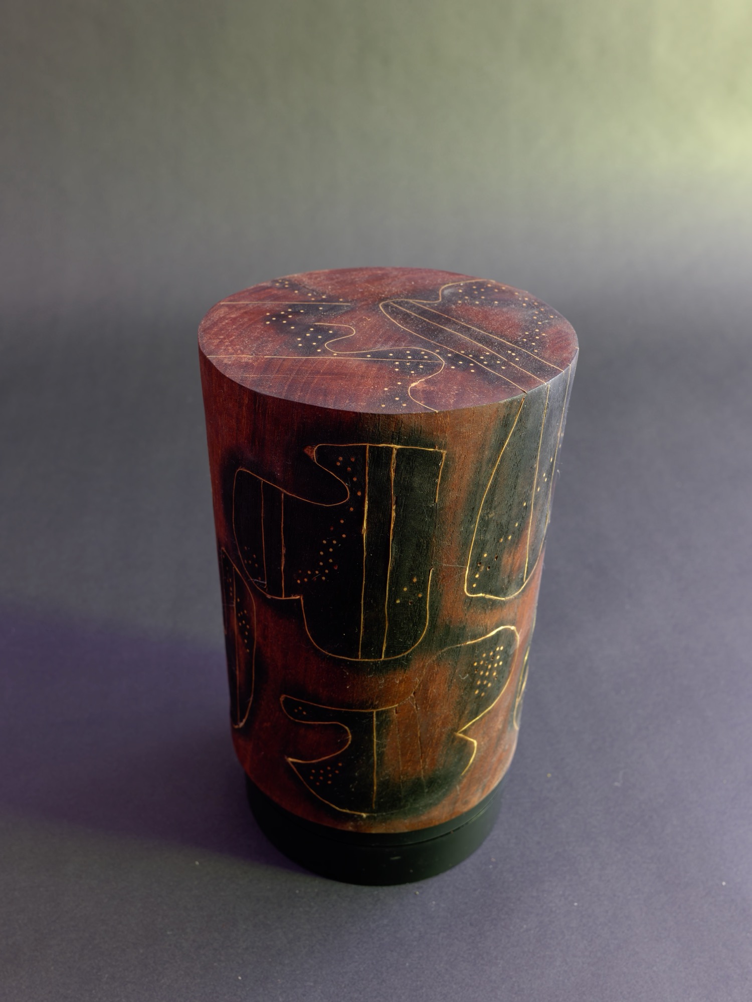 Dream — top view of a carved cylinder incised with figures, deep red and black